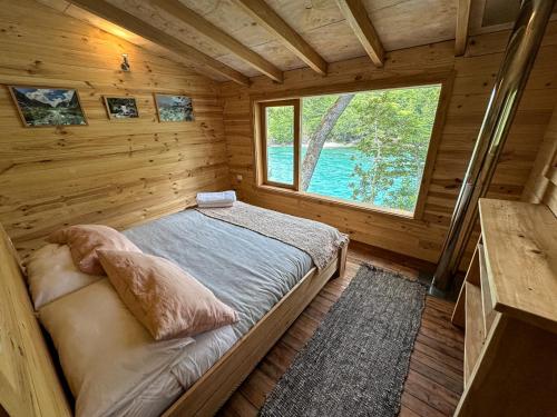 Dormitorio de una cabaña de madera con cama y ventana en Puelo Libre en Llanada Grande