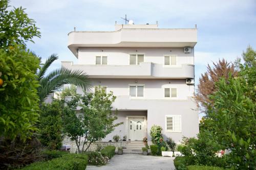 a white building with trees in front of it at Rooms by Romi in Durrës