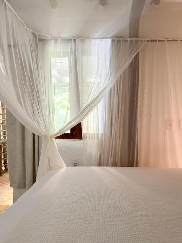 a bed with white curtains and a window at Casa da Glória Trancoso - Pousada Boutique in Trancoso
