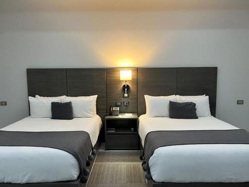 a hotel room with two beds and a lamp at Hotel GRALTA in Jalostotitlán