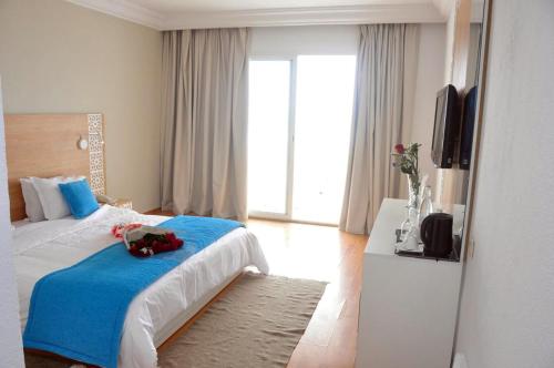 - une chambre avec un lit doté d'une couverture bleue et d'une télévision dans l'établissement TMK L'Atrium Yasmine Hammamet, à Hammamet