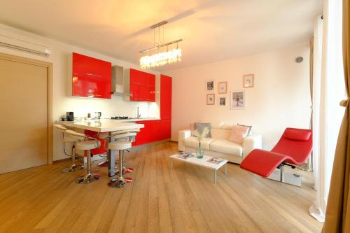 uma cozinha e sala de estar com armários vermelhos e um sofá em MIMA61 - Appartamento con giardino e posti auto a 50mt dal centro em Milano Marittima