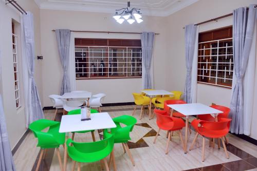 Kelly Traveller's Inn في Kakinzi: غرفة بها طاولات وكراسي ونوافذ