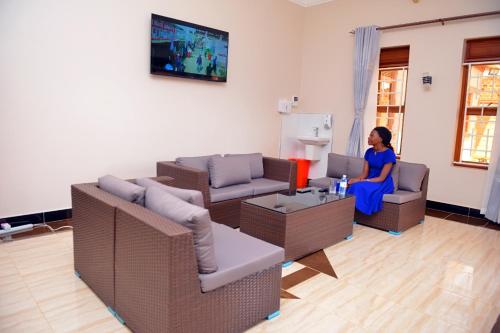 Kelly Traveller's Inn في Kakinzi: امرأة تجلس في غرفة المعيشة تشاهد التلفزيون