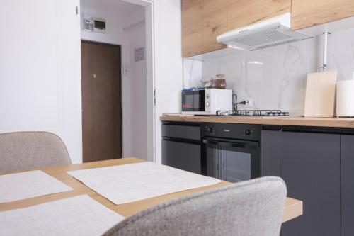 a kitchen with a table and a stove and a microwave at Konstanzer Podu Ros 11 - 3 camere,bucatarie, aer conditionat,masina de spalat in Iaşi
