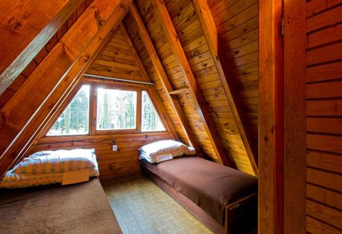 a room with two beds in a wooden cabin at Wawrzkowizna in Rząsawa