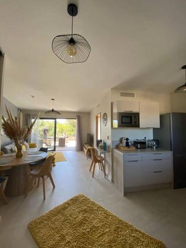 une cuisine et un salon avec une table et des chaises dans l'établissement Appartement 4 personnes - Grande terrasse - Proche du Port - Porto-Vecchio, à Porto-Vecchio