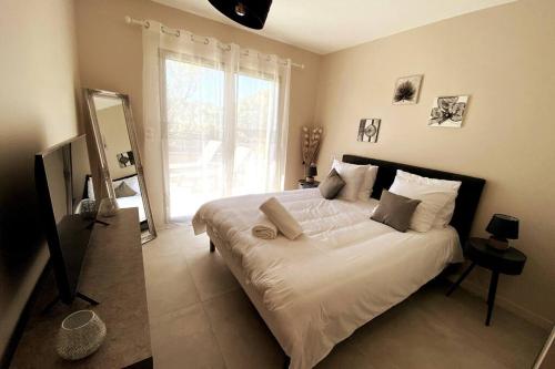 une chambre avec un grand lit blanc avec une grande fenêtre dans l'établissement Appartement 4 personnes - Grande terrasse - Proche du Port - Porto-Vecchio, à Porto-Vecchio