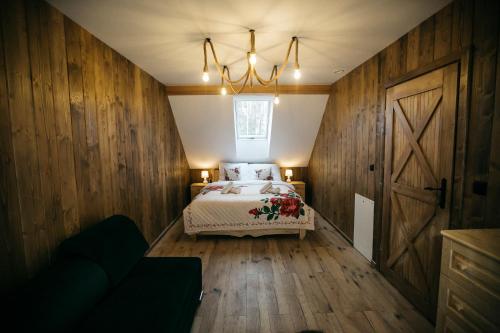 um quarto com uma cama com paredes de madeira e um lustre em Apartamenty Rogoża em Rogożnik