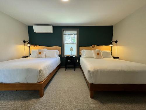 a bedroom with two beds and a desk with a window at East Rock Inn in Great Barrington