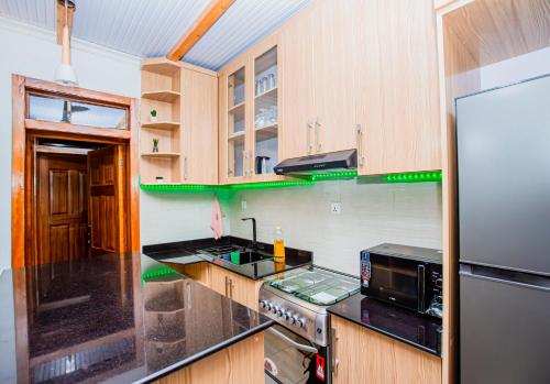 eine Küche mit Holzschränken und einem Kühlschrank aus Edelstahl in der Unterkunft Guest Suite in Kigali in Kigali