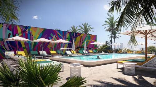 a pool with chairs and umbrellas in front of a mural at citizenM Miami South Beach in Miami Beach