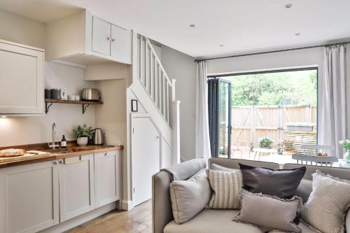 ein Wohnzimmer mit Couch und Küche in der Unterkunft Cotswold Luxury Coach House - ideal for couples, w/ EV charging in Andoversford