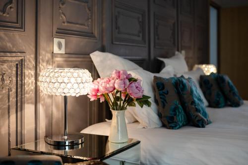 a vase of flowers on a glass table next to a bed at Château de Melin - B&B in Auxey-Duresses