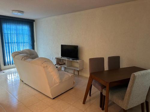 ein Wohnzimmer mit einem weißen Stuhl und einem TV in der Unterkunft Casa Vazquez Colinas Plata in Cadena