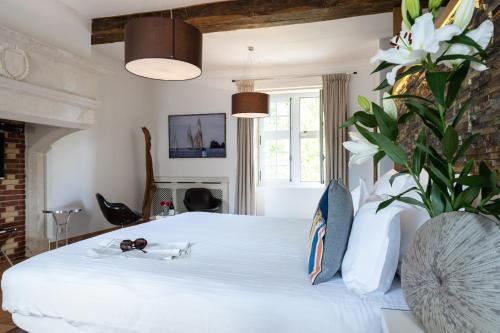 ein Schlafzimmer mit einem weißen Bett und einer Blumenvase in der Unterkunft Château de Melin - B&B in Auxey-Duresses