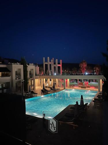 a swimming pool at night with chairs and a building at Ambrosia Hotel Beach & Spa in Bitez