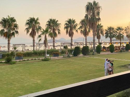 two people standing in a park with palm trees at Ambrosia Hotel Beach & Spa in Bitez