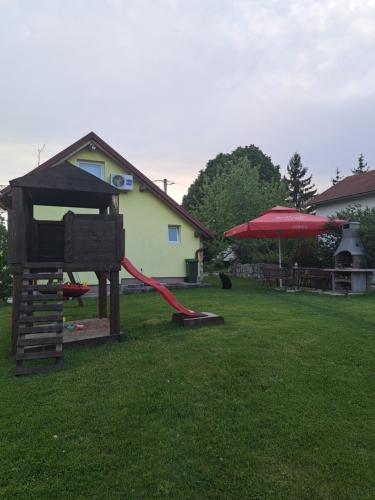 un parque infantil en un patio con un tobogán rojo en Guest house Emanuela, en Slunj