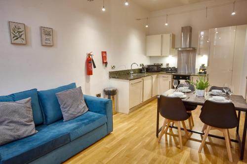 a living room with a blue couch and a table at The Amber Suite in Manchester