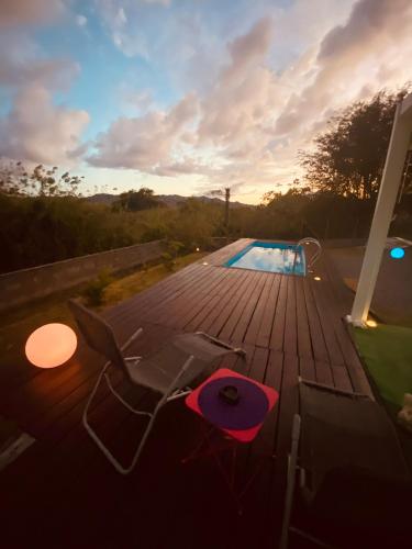a wooden deck with chairs and a swimming pool at Villa KLYTANLY in Le Robert
