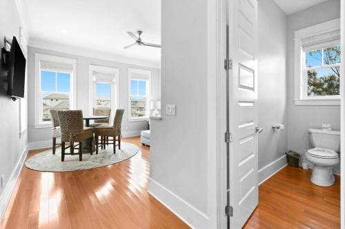 Una habitación blanca con una mesa y sillas y un baño. en La Pura Vida, en Inlet Beach