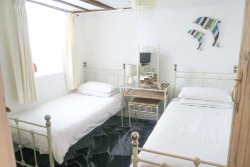 two beds in a room with a window at Hen Blas, 14th century 2 bedroom Cottage in Barmouth