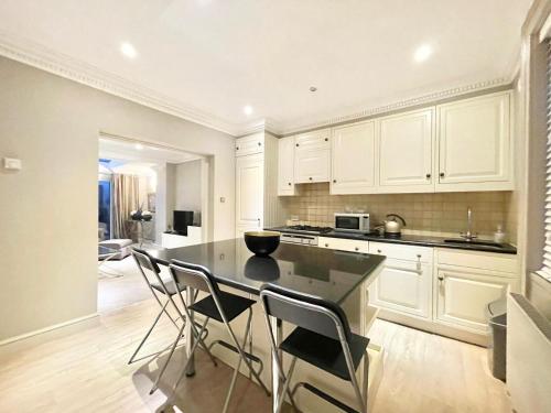 uma cozinha com armários brancos e uma mesa e cadeiras em Mayfair 2 Bedroom With Large Private Terrace em Londres