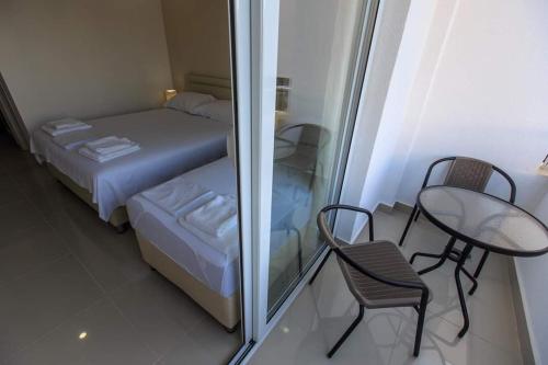 ウルツィニにあるHOME HOTEL SCANDINAVIAのベッド、テーブル、椅子が備わる小さな客室です。
