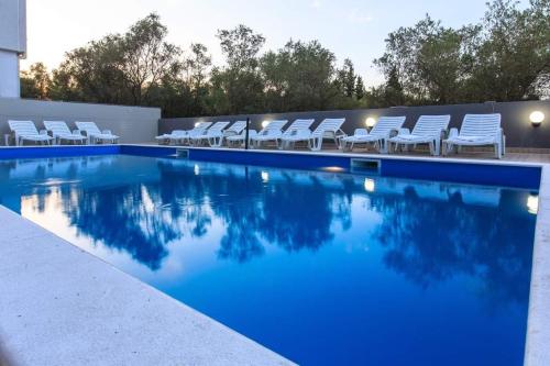 una piscina con sillas blancas y un montón de agua en HOME HOTEL SCANDINAVIA, en Ulcinj