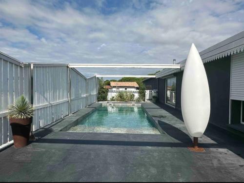 une planche de surf posée à côté d'une piscine avec une maison dans l'établissement Roof top piscine chauffée 7 pers wifi, à La Teste-de-Buch