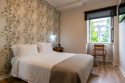 コインブラにあるオテル ヴィトーリアのベッドルーム(ベッド1台、窓付)