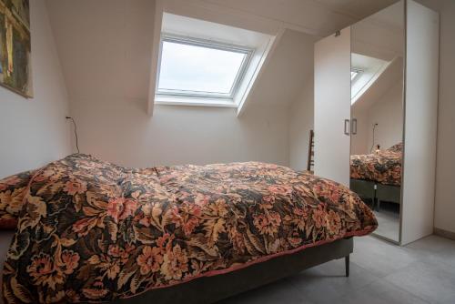 Appartementen Zee Domburg في دومبورغ: غرفة نوم بسرير ونافذة ومرآة