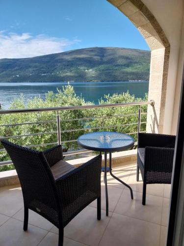 a balcony with a table and chairs and a view of the water at Apartments Villa Danilovic in Herceg-Novi