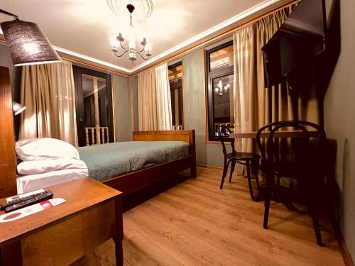 a bedroom with a bed and a table and a desk at VinoOdor - ვინოოდორ in Tʼelavi