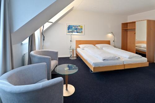 1 Schlafzimmer mit einem Bett, 2 Stühlen und einem Tisch in der Unterkunft Hotel Zofingen in Zofingen