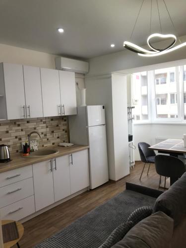 a kitchen and living room with white cabinets and a table at Light Apartments in Chernihiv