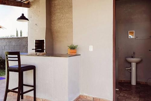 a kitchen with a bar with a chair and a sink at Villa Brisa Azul in Atibaia