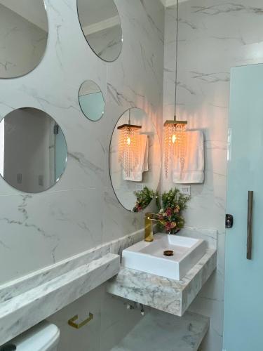 a white bathroom with a sink and mirrors at Flat luxo Capitólio in Capitólio