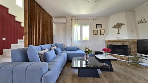 - un salon avec un canapé bleu et une cheminée dans l'établissement Alivia Garden, à Paliouri
