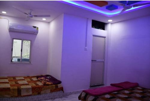 a room with two beds in a room with purple lights at Hotel Parvati Stey Home Ujjain in Ujjain