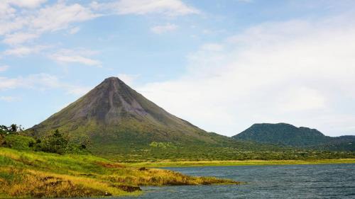 a mountain in front of a body of water at Arenal Surá in Fortuna