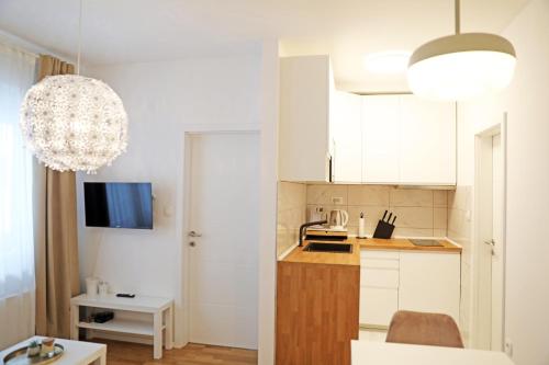 a small kitchen with white cabinets and a chandelier at Apartment Fala - self check-in 0-24, fast wi fi, city center in Zagreb