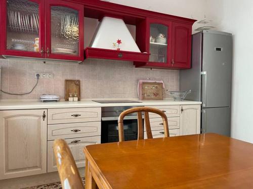 a kitchen with red cabinets and a wooden table at Komi Beach Condo with 3 Bedrooms in Chios
