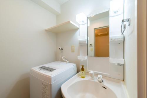 uma casa de banho branca com um lavatório e um espelho em VIDA Hakata 803 - Vacation STAY 48060v em Sumiyoshi