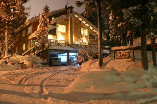 a house covered in snow in front of a house at B&B Santana Hakuba in Hakuba