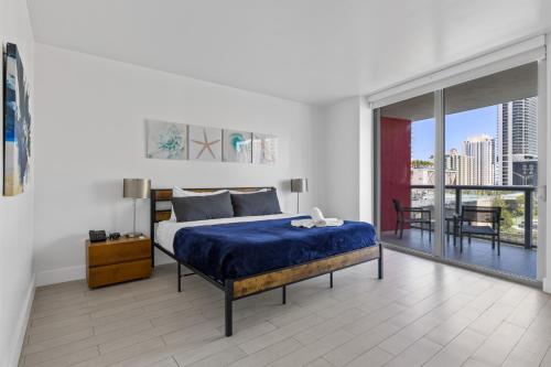 a bedroom with a blue bed and a balcony at Hallandale Sky Water View in Hallandale Beach