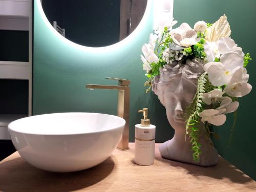 baño con lavabo y jarrón con flores en Apartament Dolina Baryczy Milicz, en Milicz