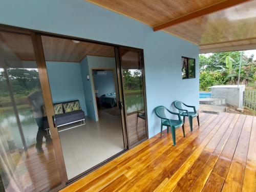 um quarto com portas de vidro e cadeiras num piso de madeira em Arenal Surá em Fortuna