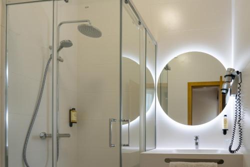 La salle de bains est pourvue d'une douche et d'un lavabo avec un miroir. dans l'établissement Hotel Vitória, à Coimbra